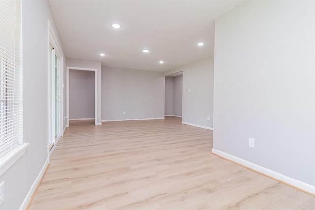 empty room with light wood-style flooring, baseboards, and recessed lighting