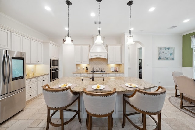 kitchen featuring stone tile floors, arched walkways, decorative backsplash, stainless steel appliances, and crown molding