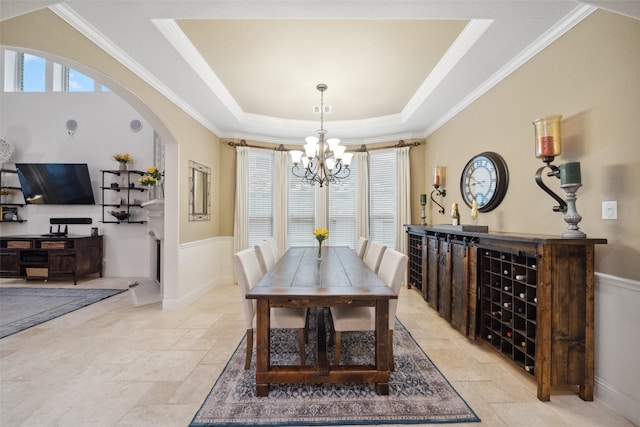 dining area featuring a raised ceiling, stone tile flooring, and a healthy amount of sunlight