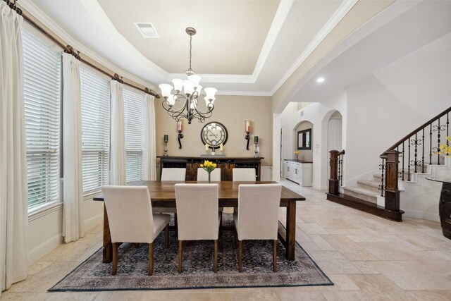 dining space with arched walkways, a chandelier, visible vents, stairs, and a raised ceiling