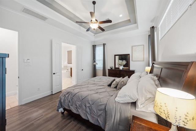 bedroom with baseboards, visible vents, wood finished floors, a tray ceiling, and crown molding