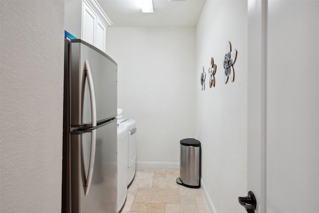 laundry room with stone tile flooring, cabinet space, washer and clothes dryer, and baseboards