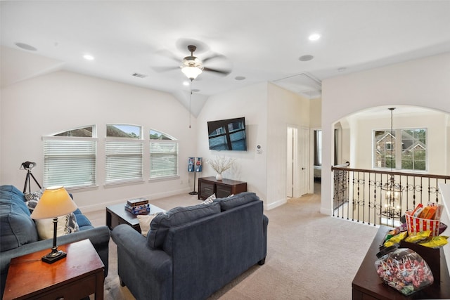 living room featuring carpet, visible vents, vaulted ceiling, and ceiling fan with notable chandelier