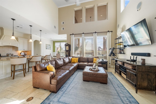 living area with stone tile floors, visible vents, a wealth of natural light, and ornamental molding