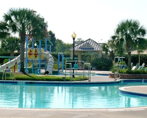 community pool with a water slide, a water play area, playground community, and a gazebo