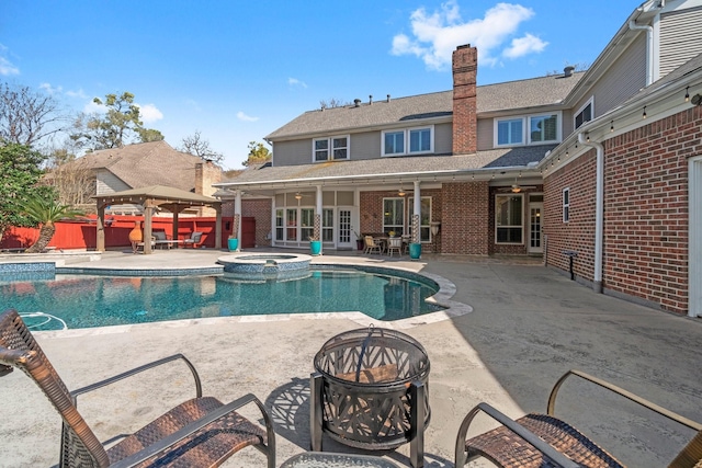 view of pool with french doors, a patio, a pool with connected hot tub, a ceiling fan, and an outdoor fire pit