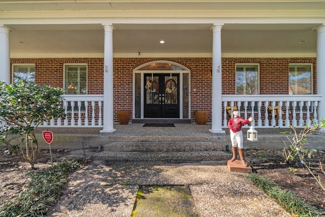 property entrance featuring covered porch and brick siding