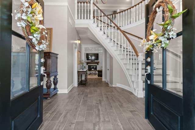 entrance foyer with wood tiled floor, a high ceiling, stairway, and baseboards