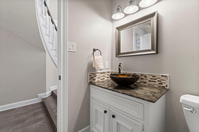 bathroom featuring toilet, baseboards, wood finished floors, and vanity