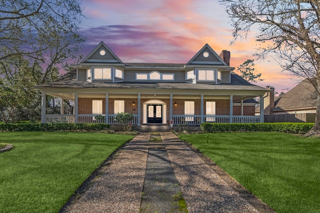 victorian-style house featuring a chimney, a front lawn, a porch, and brick siding