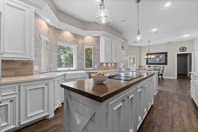 kitchen with dark wood-style flooring, backsplash, white cabinetry, butcher block countertops, and black electric cooktop