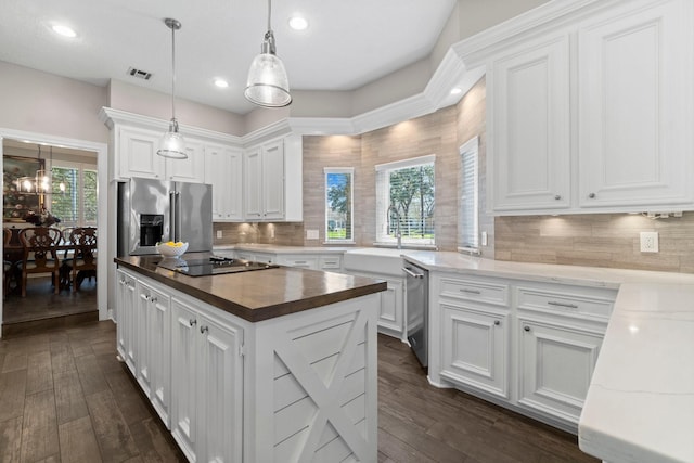 kitchen featuring dark wood-style flooring, a center island, stainless steel appliances, white cabinetry, and a sink