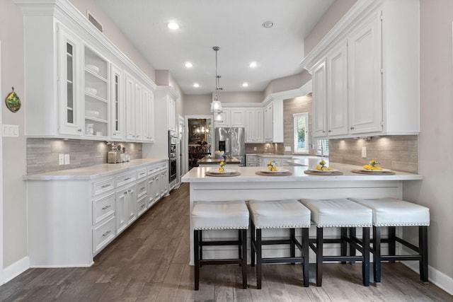 kitchen featuring glass insert cabinets, a peninsula, light countertops, white cabinetry, and stainless steel refrigerator with ice dispenser