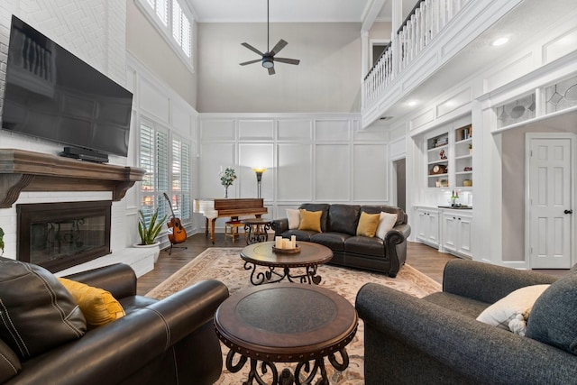 living room with a large fireplace, built in shelves, wood finished floors, and a decorative wall