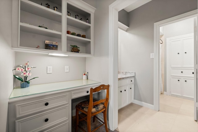 home office featuring built in study area and baseboards