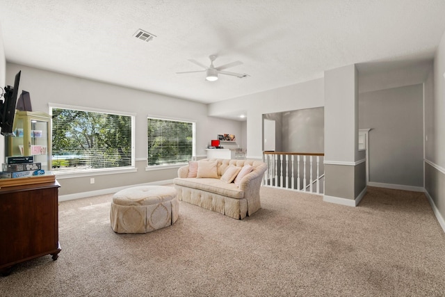 carpeted living room featuring a ceiling fan, baseboards, visible vents, and a textured ceiling