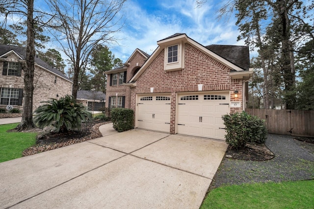 view of front facade featuring brick siding, fence, driveway, and an attached garage