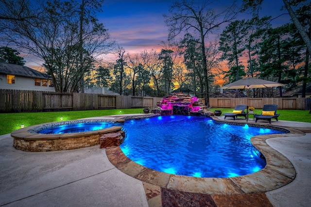 pool at dusk with a patio area, a fenced backyard, a pool with connected hot tub, and a yard