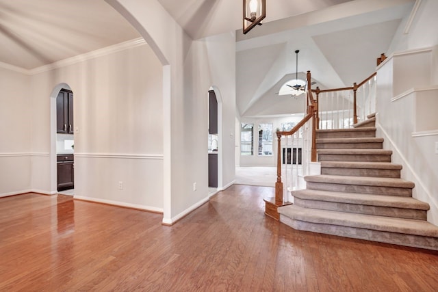 entryway with baseboards, arched walkways, a ceiling fan, wood finished floors, and stairs