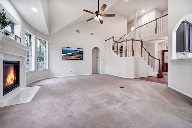 unfurnished living room featuring visible vents, baseboards, a fireplace with flush hearth, stairway, and carpet