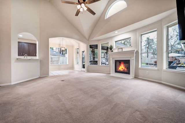 unfurnished living room with light carpet, high vaulted ceiling, a fireplace with flush hearth, and a healthy amount of sunlight