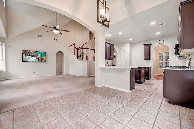 kitchen with light carpet, arched walkways, ceiling fan, open floor plan, and black microwave