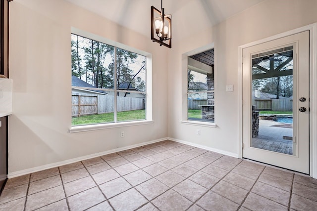 unfurnished dining area with baseboards, tile patterned floors, a notable chandelier, and a healthy amount of sunlight