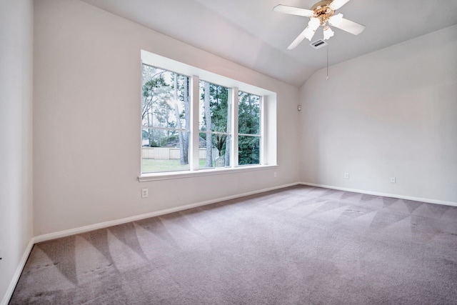 carpeted empty room featuring vaulted ceiling, ceiling fan, visible vents, and baseboards