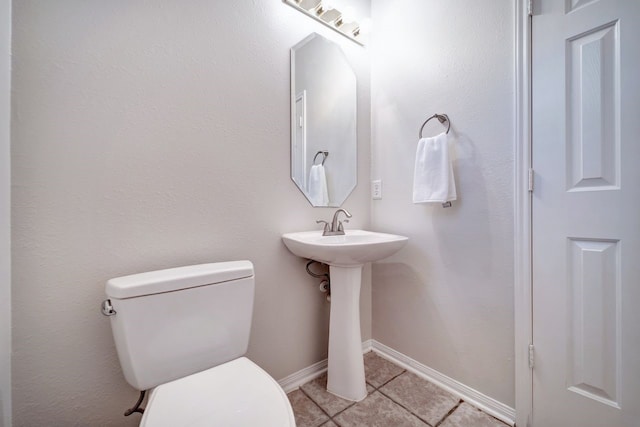 bathroom with baseboards, a sink, toilet, and tile patterned floors