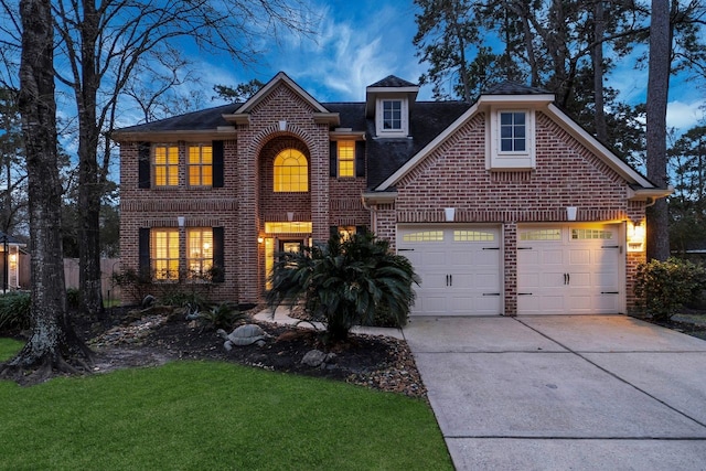 traditional home with a garage, driveway, brick siding, and a front yard