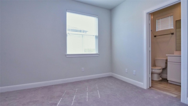 interior space with carpet flooring, baseboards, and ensuite bathroom