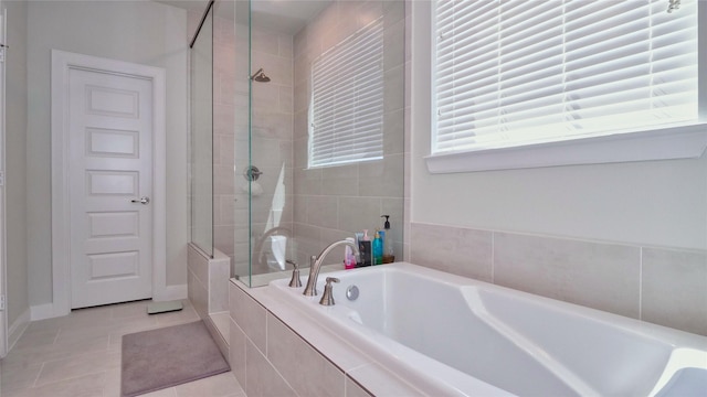 full bathroom featuring baseboards, a tile shower, a bath, and tile patterned floors