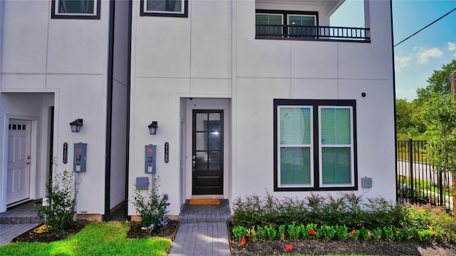 view of exterior entry featuring fence and stucco siding