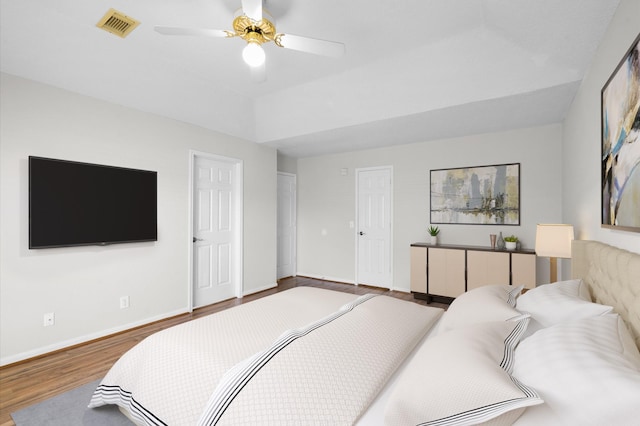 bedroom with a ceiling fan, wood finished floors, visible vents, and baseboards