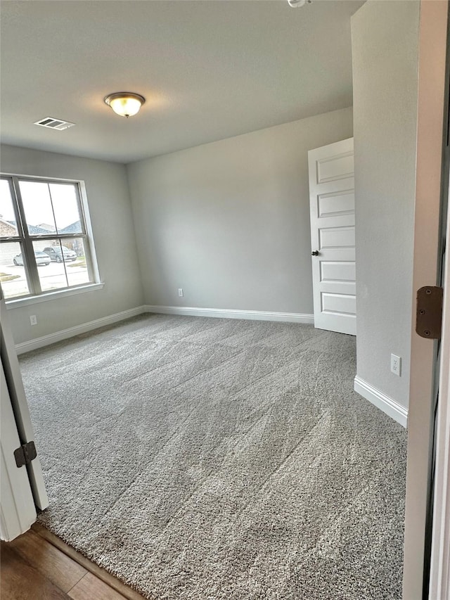 unfurnished room featuring baseboards, visible vents, and carpet flooring