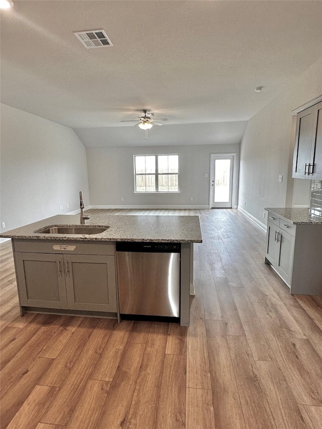 kitchen featuring light stone counters, a sink, visible vents, open floor plan, and stainless steel dishwasher