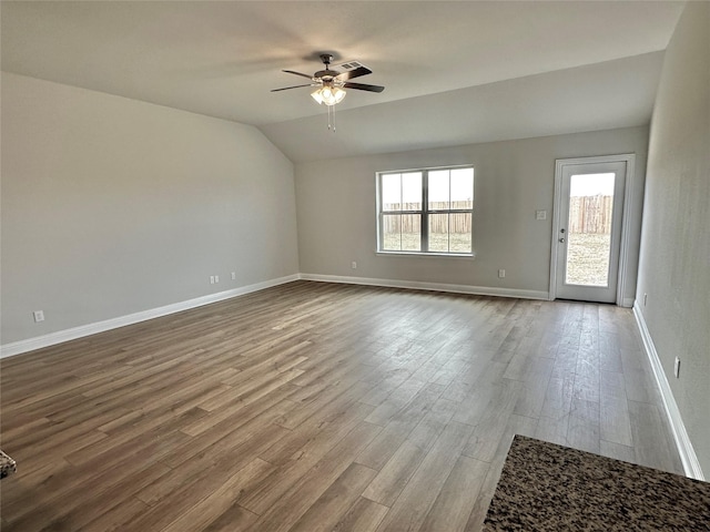 unfurnished room with a ceiling fan, baseboards, vaulted ceiling, and wood finished floors