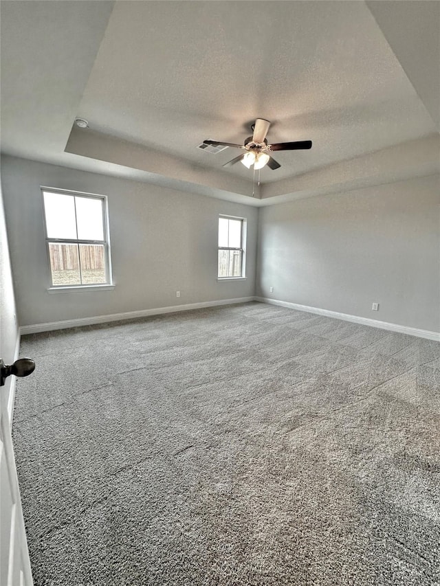 spare room with baseboards, carpet, a tray ceiling, and a textured ceiling