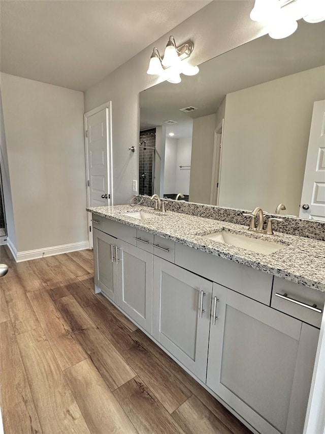 bathroom featuring a stall shower, a sink, baseboards, and wood finished floors