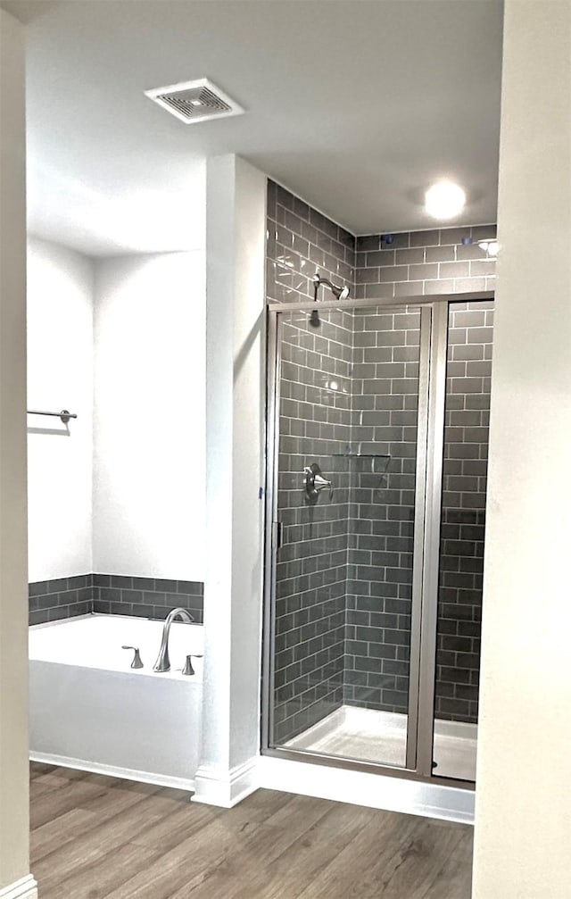 full bathroom with a stall shower, visible vents, a garden tub, and wood finished floors