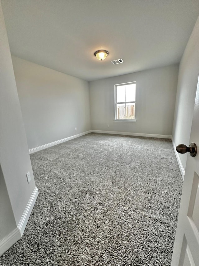 spare room with carpet flooring, visible vents, and baseboards