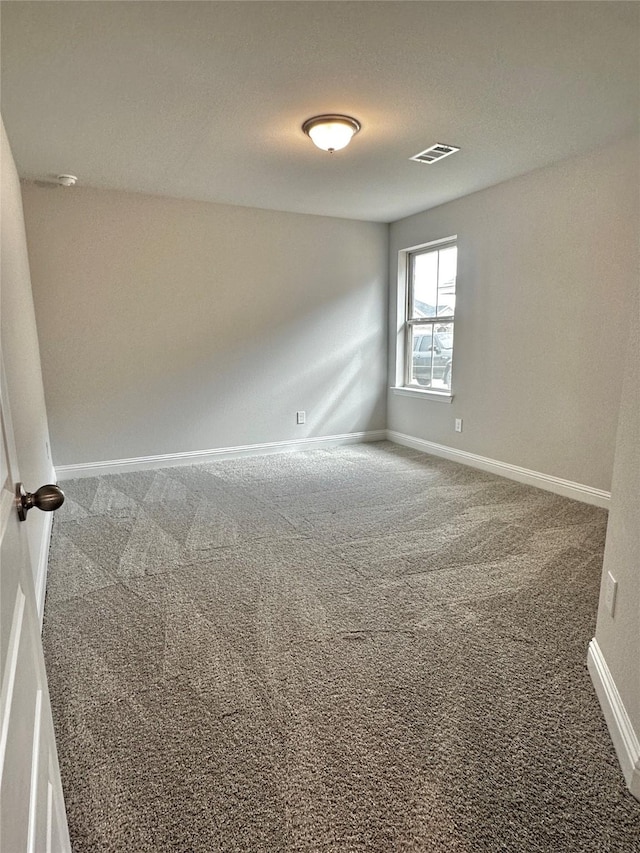 unfurnished room with carpet, visible vents, and baseboards