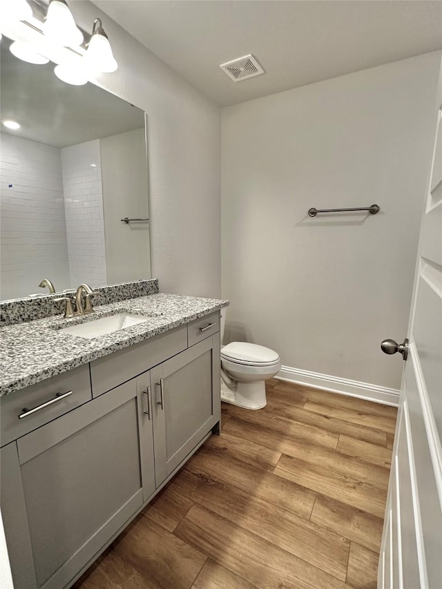 full bath with toilet, wood finished floors, vanity, visible vents, and baseboards