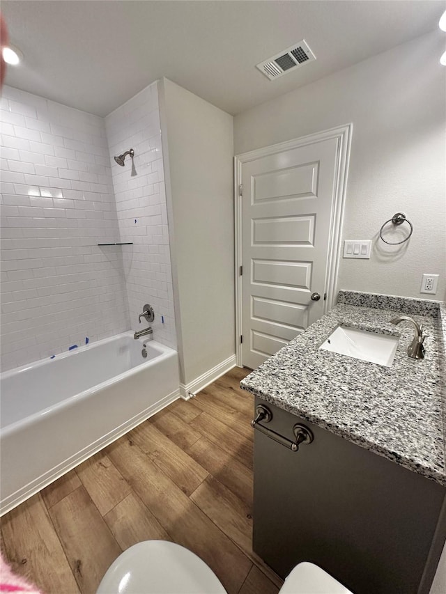 full bathroom with shower / washtub combination, visible vents, toilet, vanity, and wood finished floors