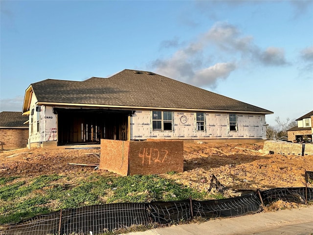 back of house featuring fence and roof with shingles