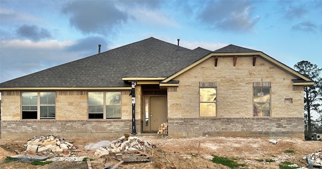 view of front of house with brick siding and roof with shingles