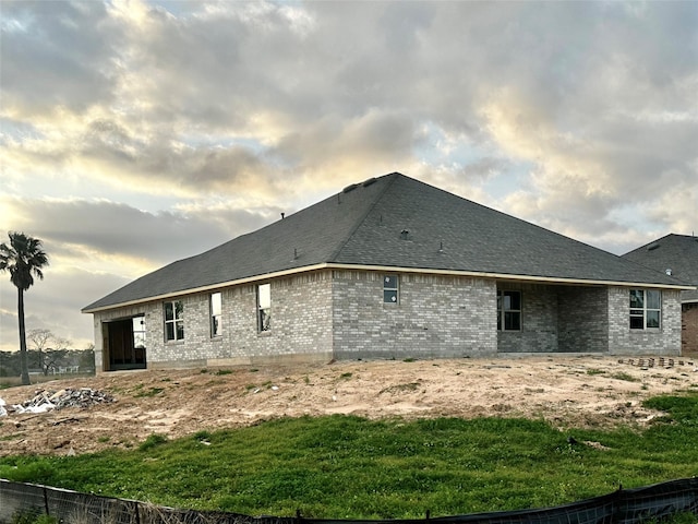 rear view of property with brick siding and roof with shingles