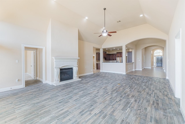 23403 Clark Arbor Ln, Katy, TX 77493 - unfurnished living room with visible vents, a fireplace with raised hearth, ceiling fan, light wood-style flooring, and high vaulted ceiling