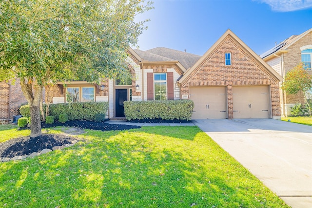 view of front of house with an attached garage, brick siding, driveway, roof with shingles, and a front yard