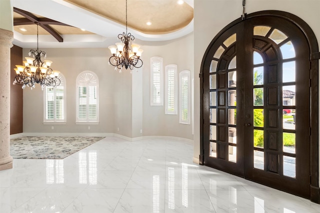 foyer entrance with arched walkways, a tray ceiling, and a notable chandelier